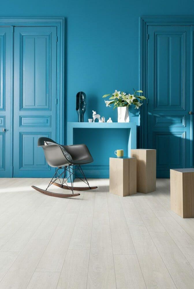 Zona de una casa con un sillón y una mesita con pared azul