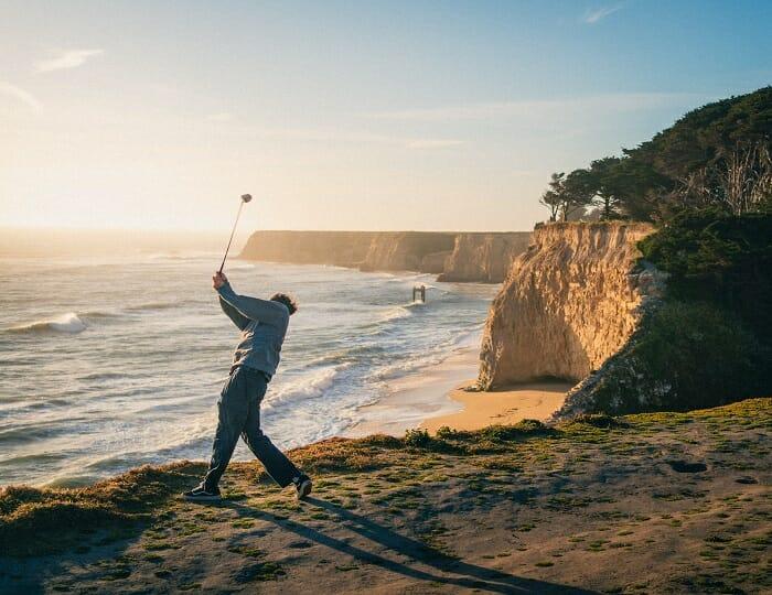 Hombre cerca del mar jugando al golf