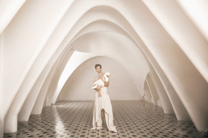 Guillermo Lorca vestido de blanco con un pato en brazos bajo un diseño de arquitectura moderno