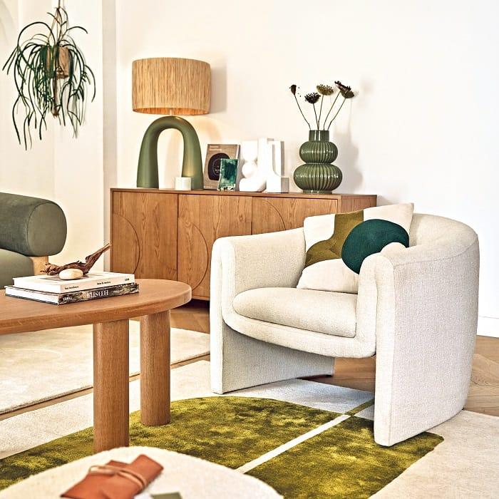 Salón con sillón blanco y una alfombra verde Maisons du Monde