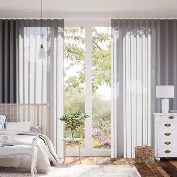 Dormitorio con cortinas blancas, mesilla y cómoda