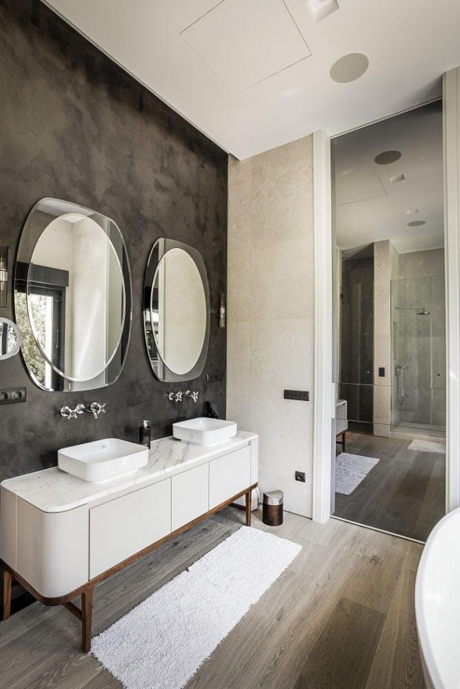 Cuarto de baño con un mueble con lavabo doble y dos espejos redondos