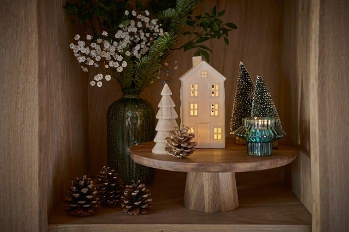 Rincón con artículos navideños como arbolitos pequeños de Navidad con iluminación led y piñas