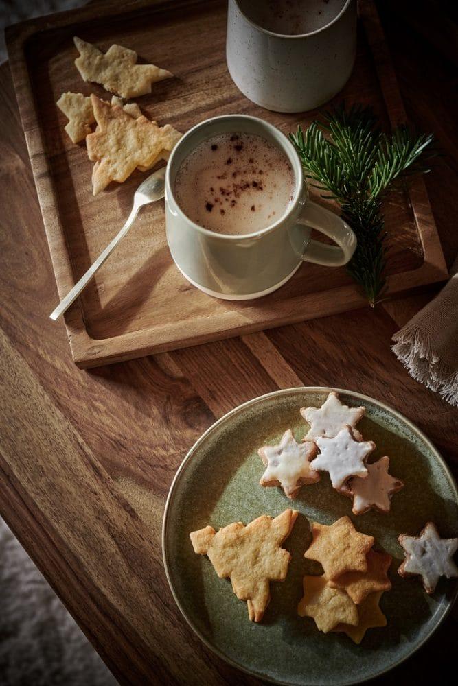Mesa con taza de leche y plato con galletas navideñas
