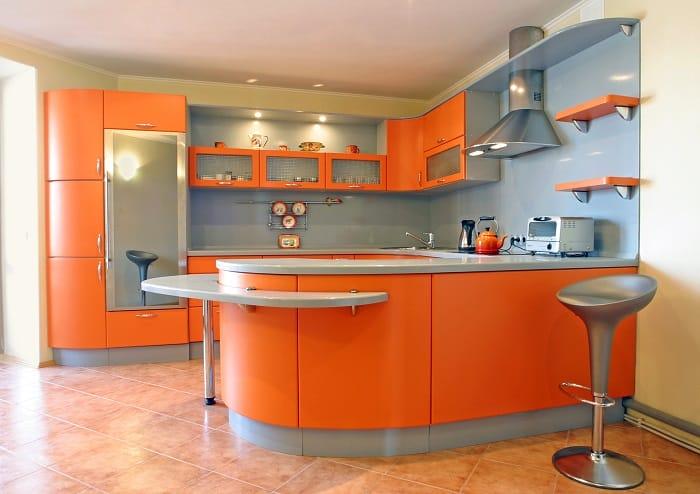 Cocina naranja moderna con isla, taburete y muebles curvos
