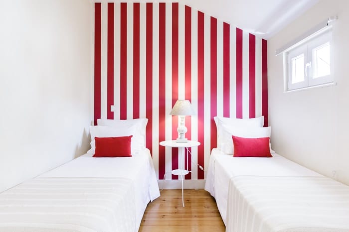 Dormitorio con dos camas individuales y pared de rayas blancas y rojas