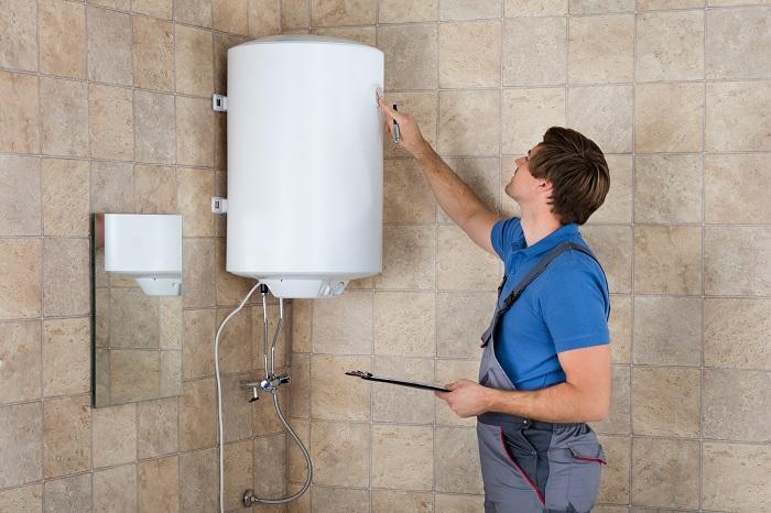 Técnico fontanero revisando un boiler eléctrico de un hogar