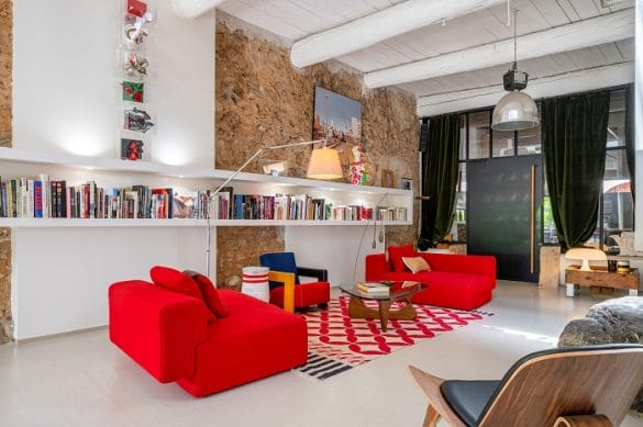 Salón con sofás rojos y estantería con libros en la pared