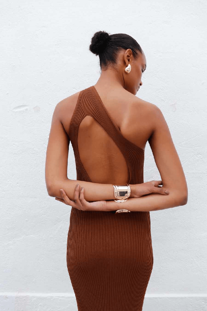 Modelo de espaldas con un vestido marrón ajustado con la espalda al aire