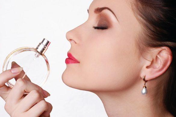 Cara de mujer de perfil oliendo un perfume abierto