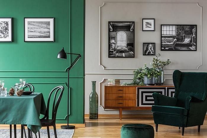 Salón con media pared en gris claro y verde con un aparador de madera