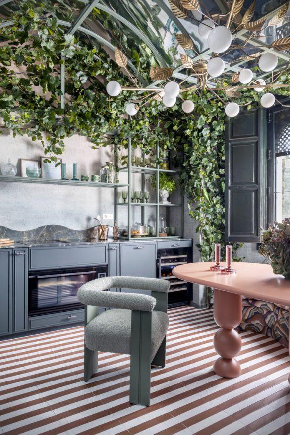 cocina con silla verde y mesa rosa con techo de plantas